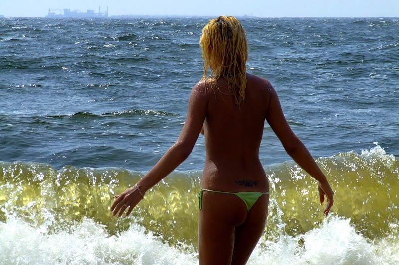 Сексуальная блондинка прогуливается топлес по пляжу